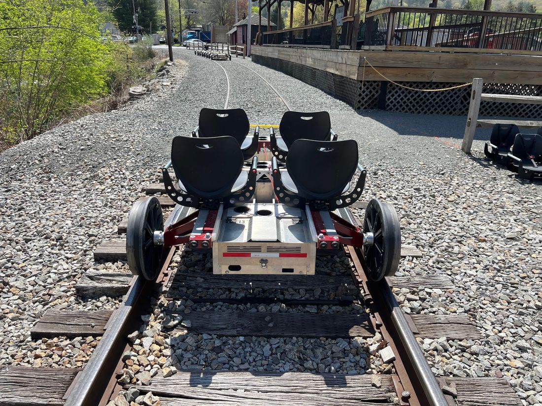 Rear view of a Rail Glider at a wooden boarding platform, with brake cords between the seats and a tow point on the back panel.
